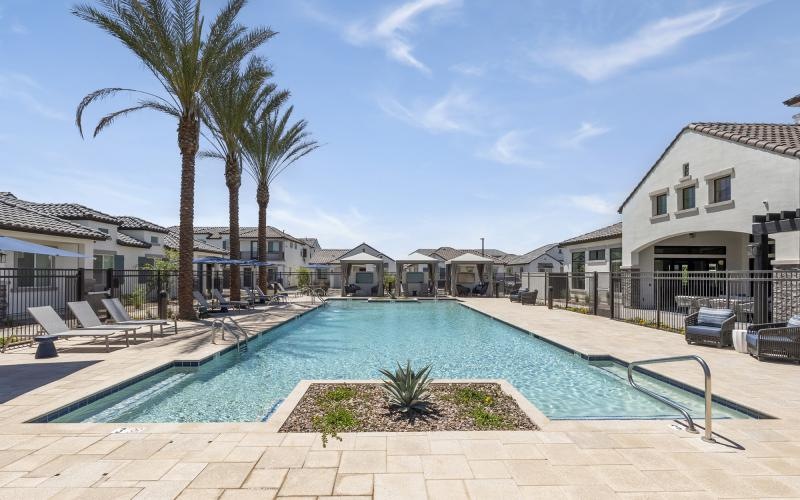 a swimming pool with palm trees and buildings in the background